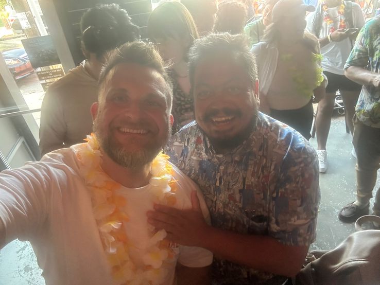 Joel and Marco, at a bar, with big smiles.