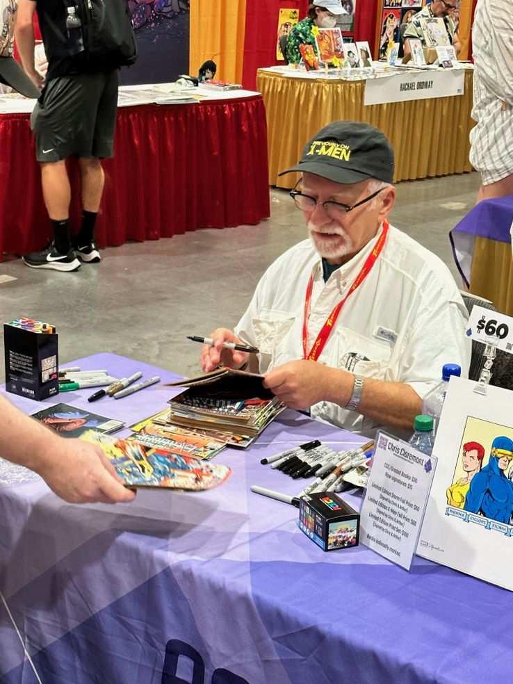 Chris Claremont signing an absurd number of books for a single attendee
